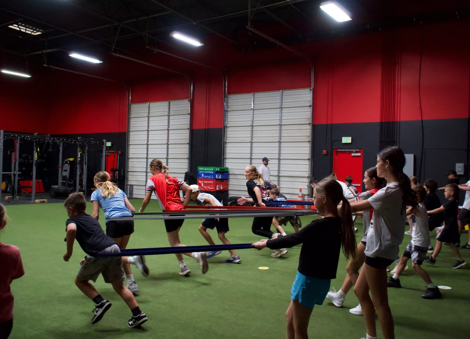 Youth athletes running a band drill across the A2Z Sports Training turf